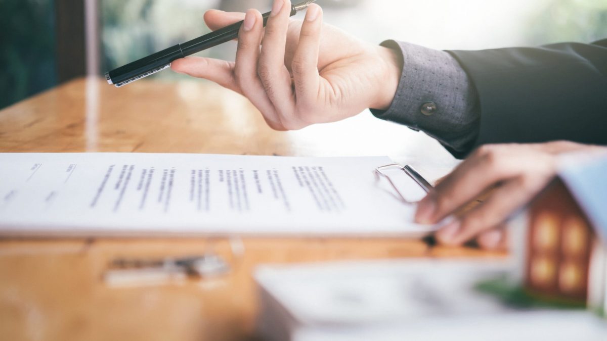 Mortgage brokers in Betheda using pen to for client to sign document.
